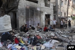رفح میں لوگ اسرائیلی بمباری کے بعد اپنے تباہ ہونے والے گھروں کے باہر ملبے کے ڈھیروں پر بیٹھے ہیں۔ 20 مئی 2024
