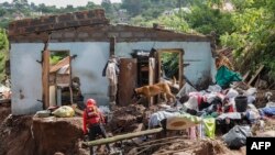 FILE - A member South African Police Services (SAPS) Search and Rescue Unit guide their sniffer dog during search efforts to locate ten people who are unaccounted for from area of KwaNdengezi township outside Durban on Apr. 15, 2022.