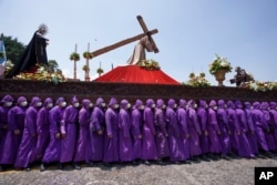 Penitentes portan una imagen de Jesucristo durante una procesión del Jueves Santo en Antigua, Guatemala, el 14 de abril de 2022.