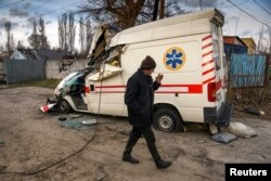 A local man walks past a damaged ambulance, as Russia's attack on Ukraine continues, in the settlement of Hostomel, outside Kyiv, Ukraine, April 6, 2022.