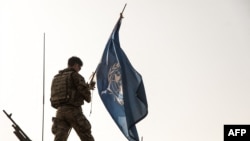 FILE: A British soldier of the United Nations Multidimensional Integrated Stabilization Mission in Mali (MINUSMA), adjusts a UN flag on the roof of a armored vehicle during a patrol in Menaka, Mali. Taken October 28, 2021. 