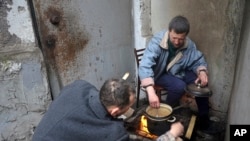 Жители Мариуполя готовят еду на импровизированном очаге у входа в здание, разрушенном в ходе войны. 13 апреля 2022 года. 