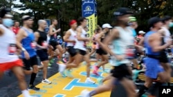FILE - Runners cross the starting line of the 125th Boston Marathon, in Hopkinton, Massachusetts, Oct. 11, 2021. The 2022 marathon returns to the streets on April 18.