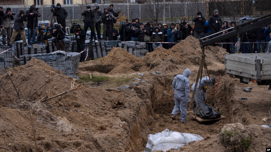 Pekerja pemakaman menggali mayat seorang warga sipil yang tewas di Bucha dari kuburan massal, di pinggiran Kyiv, Ukraina, Rabu, 13 April 2022. (Foto: AP)