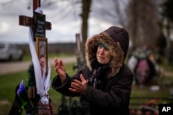 Valentyna Nechyporenko, 77, mourns at the grave of her 47-year-old son Ruslan, during his funeral at the cemetery in Bucha, on the outskirts of Kyiv, April 18, 2022. Ruslan was killed by Russian army on March 17 while delivering humanitarian aid to his neighbors in the streets of Bucha.