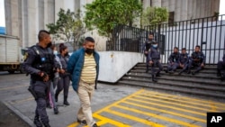 Un sospechoso de pertenecer a una red de trata de personas es escoltado por un oficial al final de su audiencia en la corte, en Ciudad de Guatemala, el 4 de febrero de 2022.