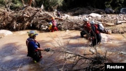 A search and rescue team works with sniffer dogs to recover bodies from the Mzinyathi River near Durban, South Africa, April 19, 2022