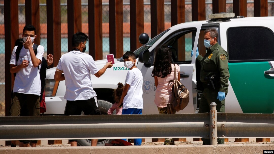FILE - Asylum-seeking migrants are detained by a U.S. Border Patrol agent after crossing the Rio Bravo river, in El Paso, Texas, as seen from Ciudad Juarez, Mexico, April 6, 2022. 