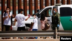 FILE - Asylum-seeking migrants are detained by a U.S. Border Patrol agent after crossing the Rio Bravo river, in El Paso, Texas, as seen from Ciudad Juarez, Mexico, April 6, 2022. 