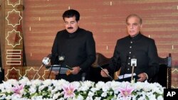 In this photo released by Press Information Department, acting President of Pakistan Sadiq Sanjrani, left, administers the oath of office to newly elected Pakistani Prime Minister Shahbaz Sharif at Presidential Palace in Islamabad, April 11, 2022