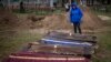 Ira Slepchenko cries next to coffins, one of them holding the body of her husband Sasha Nedolezhko, during an exhumation of a mass grave in Mykulychi, Ukraine, April 17, 2022.