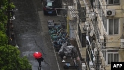 A woman shelters from the rain with an umbrella while walking along a deserted street during a COVID-19 coronavirus lockdown in the Jing'an district in Shanghai, April 13, 2022.