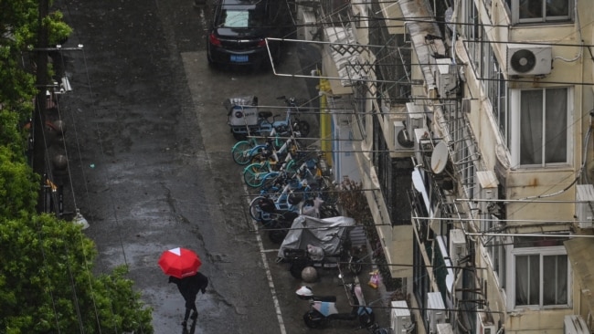 A woman shelters from the rain with an umbrella while walking along a deserted street during a COVID-19 coronavirus lockdown in the Jing'an district in Shanghai, April 13, 2022.