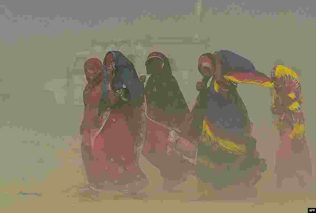 People walk through a sand storm at the Sangam, the confluence of the rivers Ganges, Yamuna and mythical Saraswati in Allahabad, India.