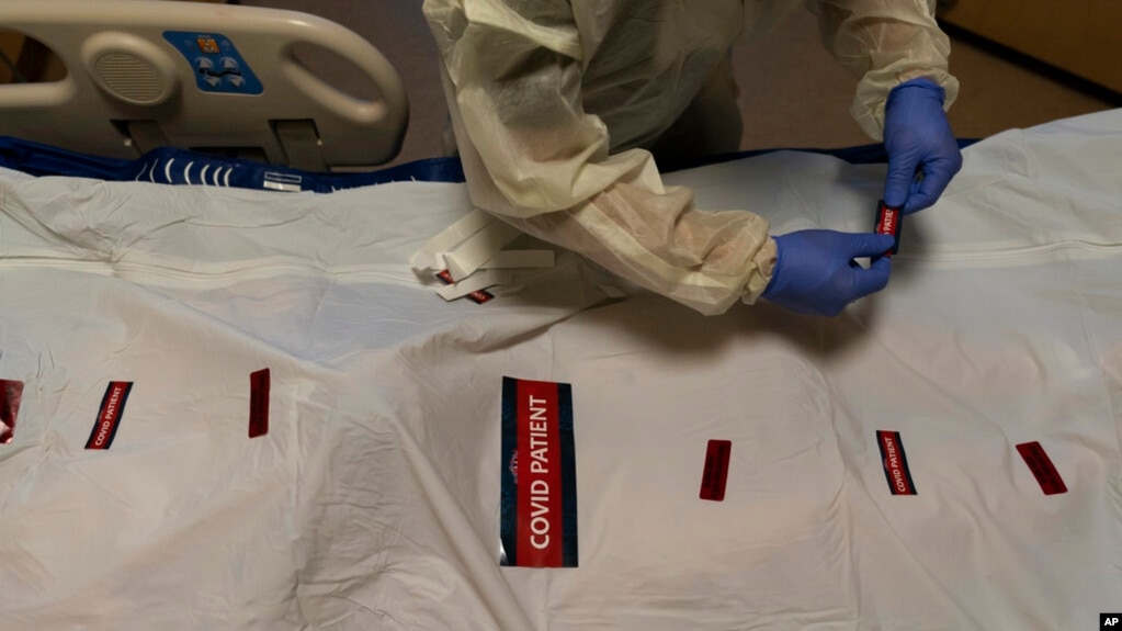 FILE - A nurse attaches "COVID Patient" stickers on a body bag of a patient who died of coronavirus at Providence Holy Cross Medical Center in Los Angeles, Dec. 14, 2021.