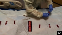 FILE - A nurse attaches "COVID Patient" stickers on a body bag of a patient who died of coronavirus at Providence Holy Cross Medical Center in Los Angeles, Dec. 14, 2021.