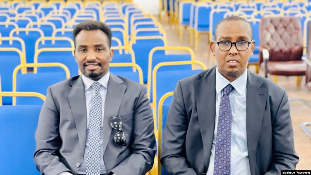 Saadaq John (Midigta)  iyo Afhayeenka Xukuumadda Maxamed Ibraahim Macallimuu oo ka mid ah xildhibaannada cusub ee Baarlamaanka 11-aad oo fadhiya hoolka dhaarta.
