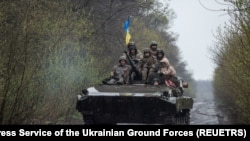 Ukrainian servicemen ride atop an armored fighting vehicle at an unknown location in Eastern Ukraine, in this handout picture released April 19, 2022.
