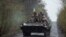 Ukrainian servicemen ride atop an armored fighting vehicle at an unknown location in Eastern Ukraine, in this handout picture released April 19, 2022.