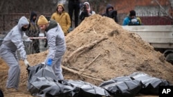 Men wearing protective gear exhume the bodies of civilians killed during the Russian occupation in Bucha, in the outskirts of Kyiv, Ukraine, April 13, 2022. 