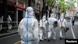 Petugas mengenakan pakaian hazmat saat melakukan penyiraman disinfektan di kawasan perumahan yang terkena lockdown di Shanghai, China, pada 15 April 2022. (Foto: Reuters/Aly Song)