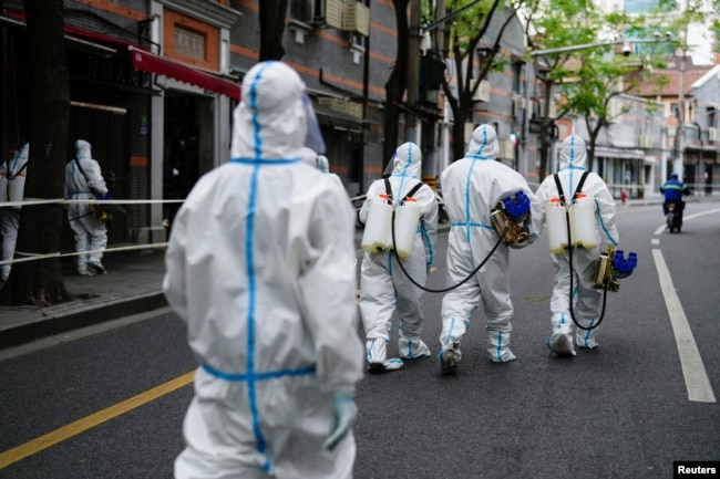 FILE - Workers in protective suits disinfect an old residential area under lockdown amid the coronavirus disease (COVID-19) pandemic, in Shanghai, China, Apr. 15, 2022. (REUTERS/Aly Song)