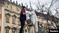 Workers wrap a statue to protect it in case of possible shelling in Lviv, Ukraine, amid Russia's invasion of Ukraine, March 3, 2022. 