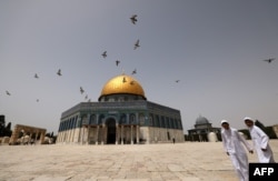 FILE - Palestinian Muslims walk in front of the Dome of Rock mosque at the Al-Aqsa mosque compound in Jerusalem's Old City, Apr. 17, 2022.