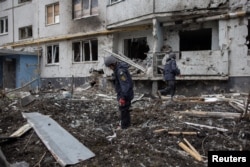 Members of the Demining Unit of the State Emergency Service inspect the area around a heavily damaged apartment block, following an artillery attack in Kharkiv, Ukraine, April 13, 2022.