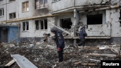 Members of the Demining Unit of the State Emergency Service inspect the area around a heavily damaged apartment block, following an artillery attack in Kharkiv, Ukraine, April 13, 2022. 