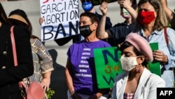 File- People hold placards as they protest against Florida's 15-week abortion ban in front of the office of State Senator Ileana Garcia,a strong supporter of the ban, in Coral Gables, Florida, Jan. 21, 2022.