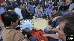 Warga Kurdi berkumpul di pasar yang populer di Arbil, ibu kota wilayah otonomi Kurdi di Irak utara, setelah matahari terbenam untuk makan dan bermain permainan tradisional, termasuk kartu dan domino dan Mheibes, pada bulan suci Ramadan, 11 Mei 2020.(Foto: SAFIN HAMED / AFP)