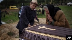 Nadiya Trubchaninova, 70, cries next to the coffin of her son Vadym, 48, who was killed by Russian soldiers March 30, 2022, in Bucha, during his funeral in the cemetery of Mykulychi, in the outskirts of Kyiv, Ukraine, April 16, 2022.
