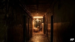 A family sits in the hallway of their apartment building as Russian attacks continue, in Kharkiv, Ukraine, April 15, 2022.