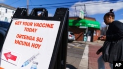 FILE - A sign promoting available COVID-19 vaccines stands outside a vaccination clinic in Providence, R.I., March 3, 2022. State statistics now show 99% of Rhode Island adults are at least partially vaccinated and 48% have gotten a booster dose.