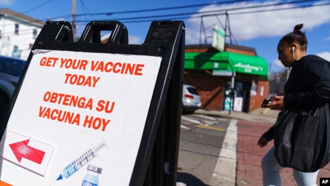 FILE - A sign promoting available COVID-19 vaccines stands outside a vaccination clinic in Providence, R.I., March 3, 2022. State statistics now show 99% of Rhode Island adults are at least partially vaccinated and 48% have gotten a booster dose.