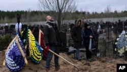 Artem, trabajador del cementerio, mira al cielo exhausto, mientras trabaja en la tumba de Andriy Verbovyi, de 55 años, muerto durante la ofensiva rusa mientras servía en la defensa territorial de Bucha, en las afueras de Kiev, Ucrania, el miércoles 13 de abril de 2022.