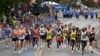 FILE - Elite runners make navigate the first mile of the 125th Boston Marathon, Oct. 11, 2021. 
