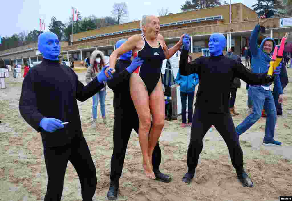 A swimmer is lifted by the members of the Blue Man Group, who performed at the opening day of the pool season at the Wannsee lido in Berlin.