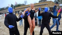 A swimmer is lifted by the members of the Blue Man Group, who performed at the opening day of the pool season at the Wannsee lido in Berlin.