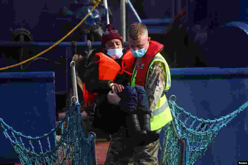 A member of the British military assists a migrant woman arriving at Britain&#39;s Port of Dover after being rescued while crossing the English Channel. (REUTERS/Hannah McKay)