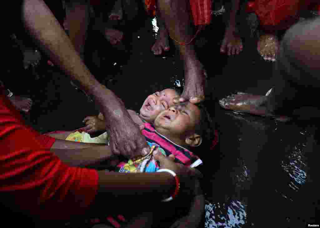 Hindu devotees touch babies with their feet as part of a special event to bless them during a religious procession for the Gajan festival, in Kolkata, India, April 13, 2022.