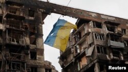 馬里烏波爾市一棟被戰火摧毀的大樓前面懸掛著烏克蘭國旗（2022年4月14日）