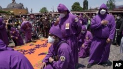 "Cucuruchos" ante paso de carroza durante una procesión del Jueves Santo, en Antigua, Guatemala (Foto Moisés Castillo /AP)