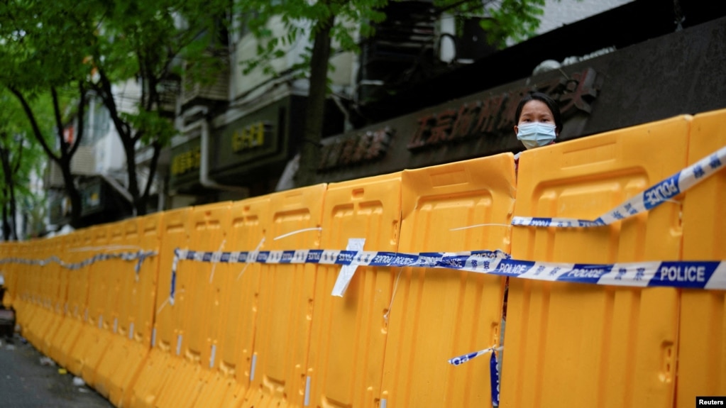 上海封城后一名女子从围栏后向外张望。（2022年4月13日）(photo:VOA)