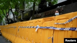 上海封城后一名女子从围栏后向外张望。（2022年4月13日）