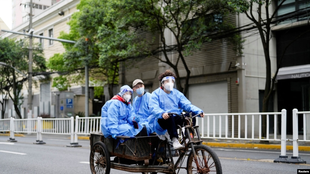 上海疫情防控人员坐电动三轮车行驶在商家关闭、空荡荡的上海街头(photo:VOA)