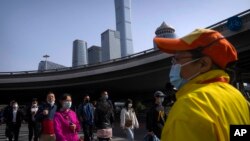 Commuters wearing face masks walk across an intersection in the central business district in Beijing, April 12, 2022.