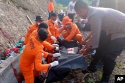 Tim penyelamat memasukkan jenazah korban ke dalam kantong jenazah usai kecelakaan truk di Manokwari, Papua Barat, Indonesia, Rabu, 13 April 2022. (BASARNAS via AP)