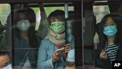 Commuters wearing face masks to help protect from the coronavirus look out from a crowded traveling bus during the morning rush hour, Monday, April 18, 2022, in Beijing. (AP Photo/Andy Wong)